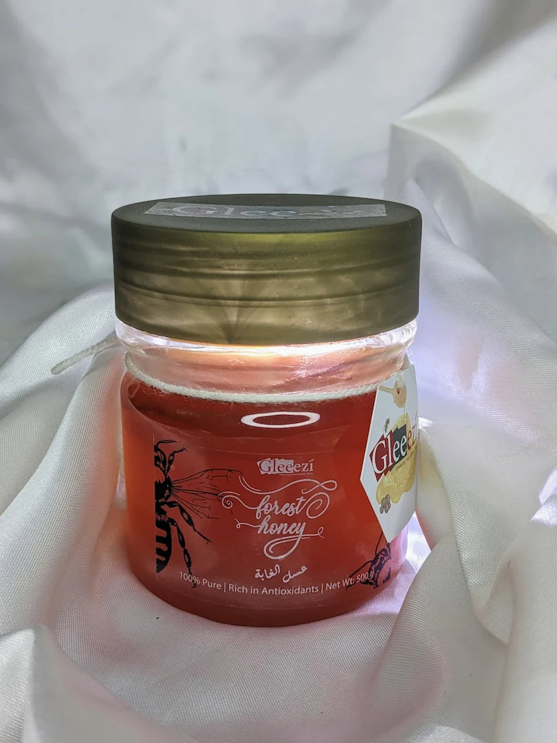 Jar of 500gram forest honey on a white fabric background.